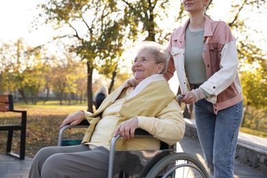 Photo of Caregiver with elderly woman in wheelchair at park