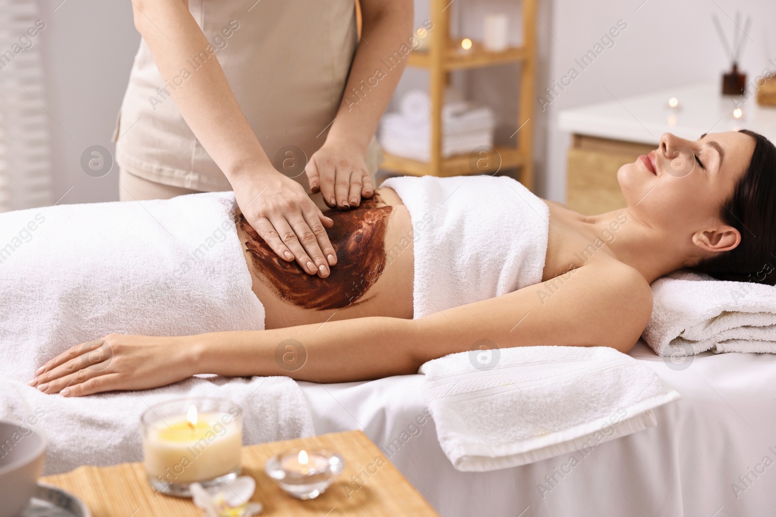 Photo of Woman undergoing chocolate body wrap treatment in spa salon