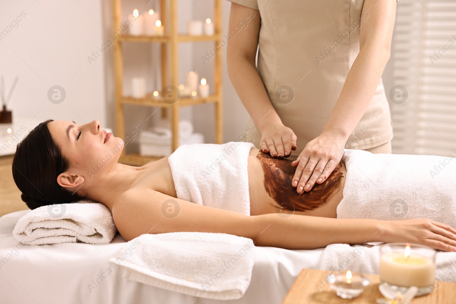 Photo of Woman undergoing chocolate body wrap treatment in spa salon