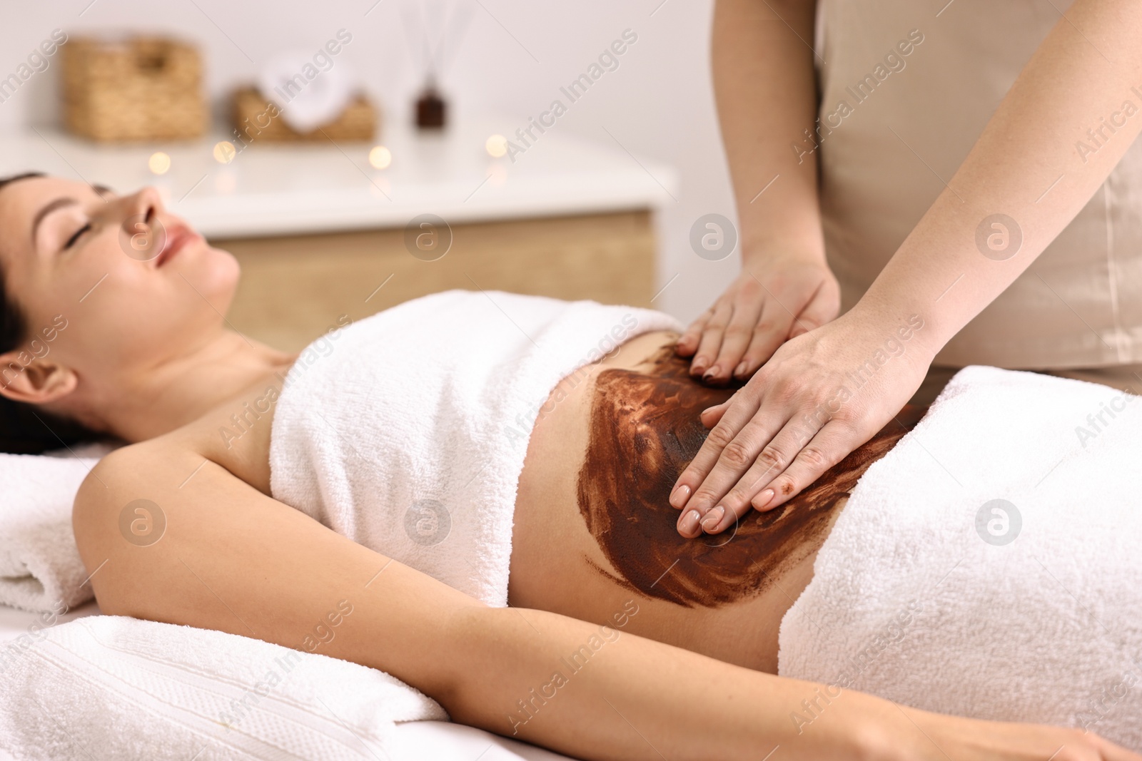 Photo of Woman undergoing chocolate body wrap treatment in spa salon