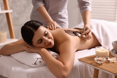 Chocolate body wrap. Spa worker applying mask onto woman's back in salon, closeup