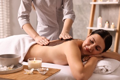 Photo of Woman undergoing chocolate body wrap treatment in spa salon