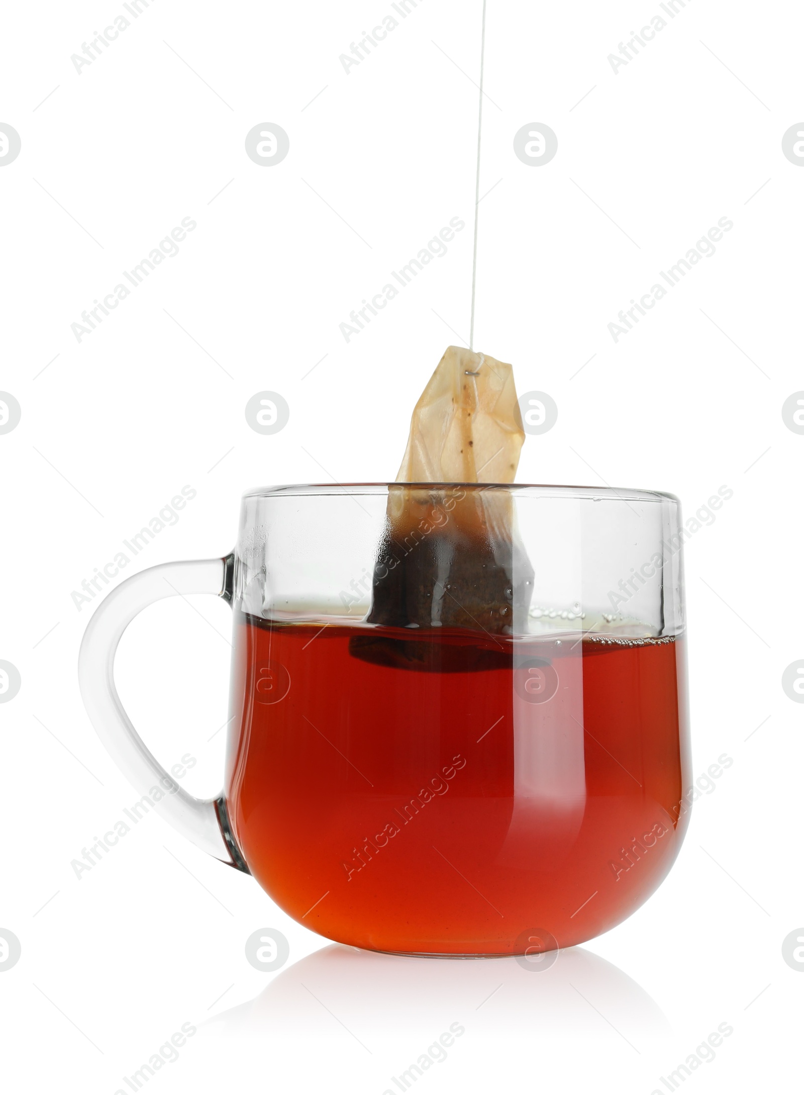 Photo of Putting tea bag into glass cup on white background