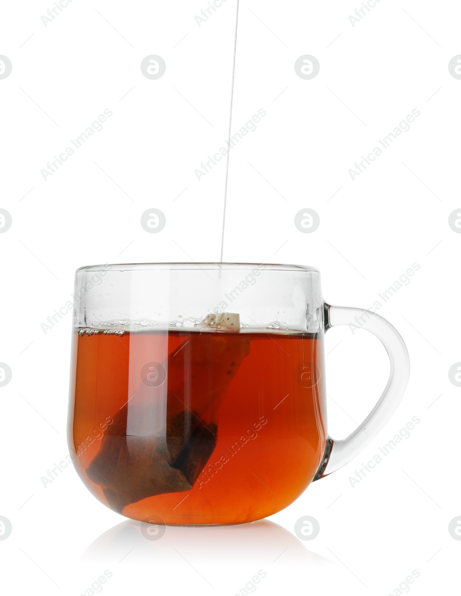 Photo of Putting tea bag into glass cup on white background