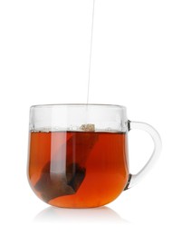 Photo of Putting tea bag into glass cup on white background