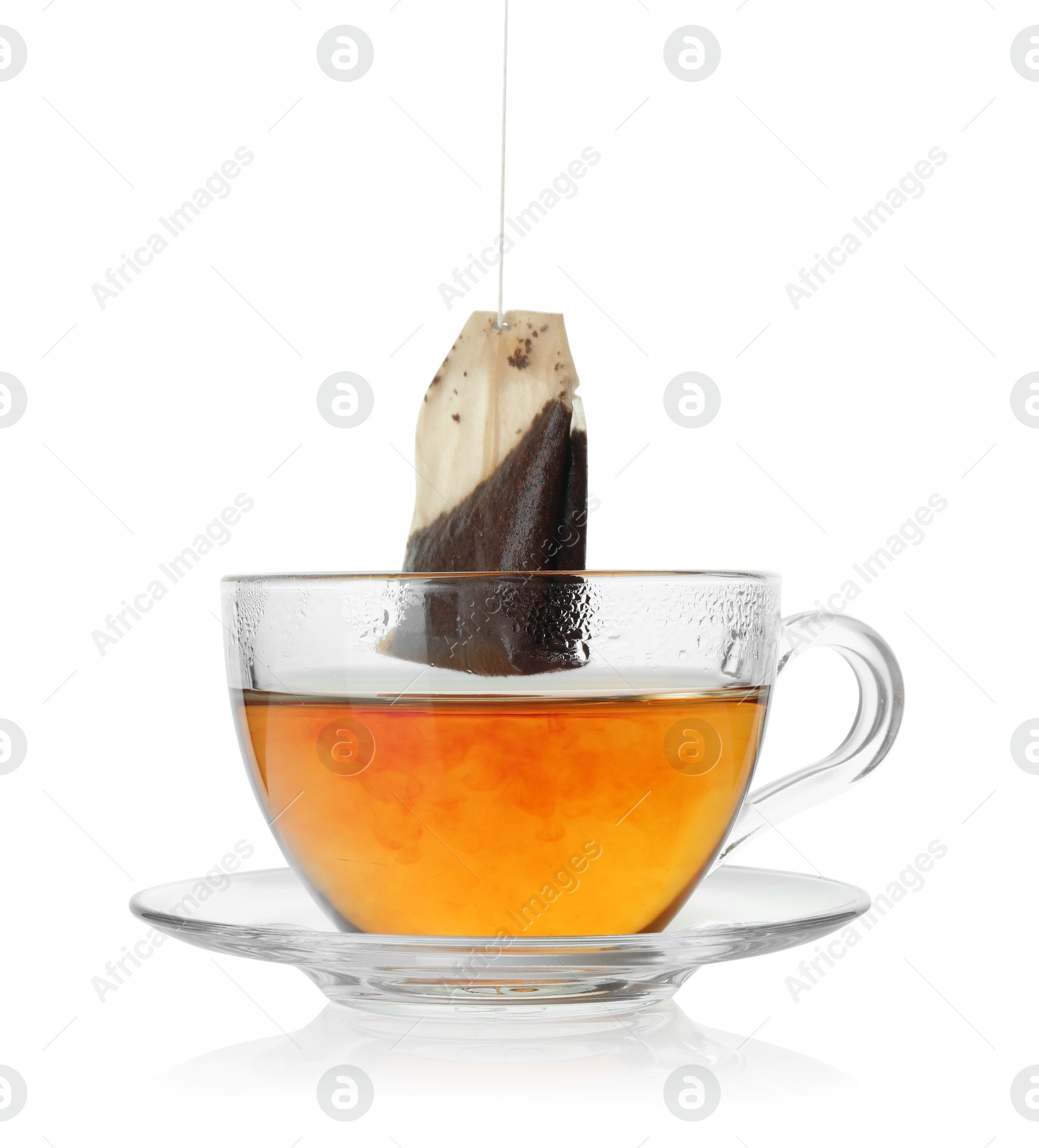 Photo of Putting tea bag into glass cup on white background