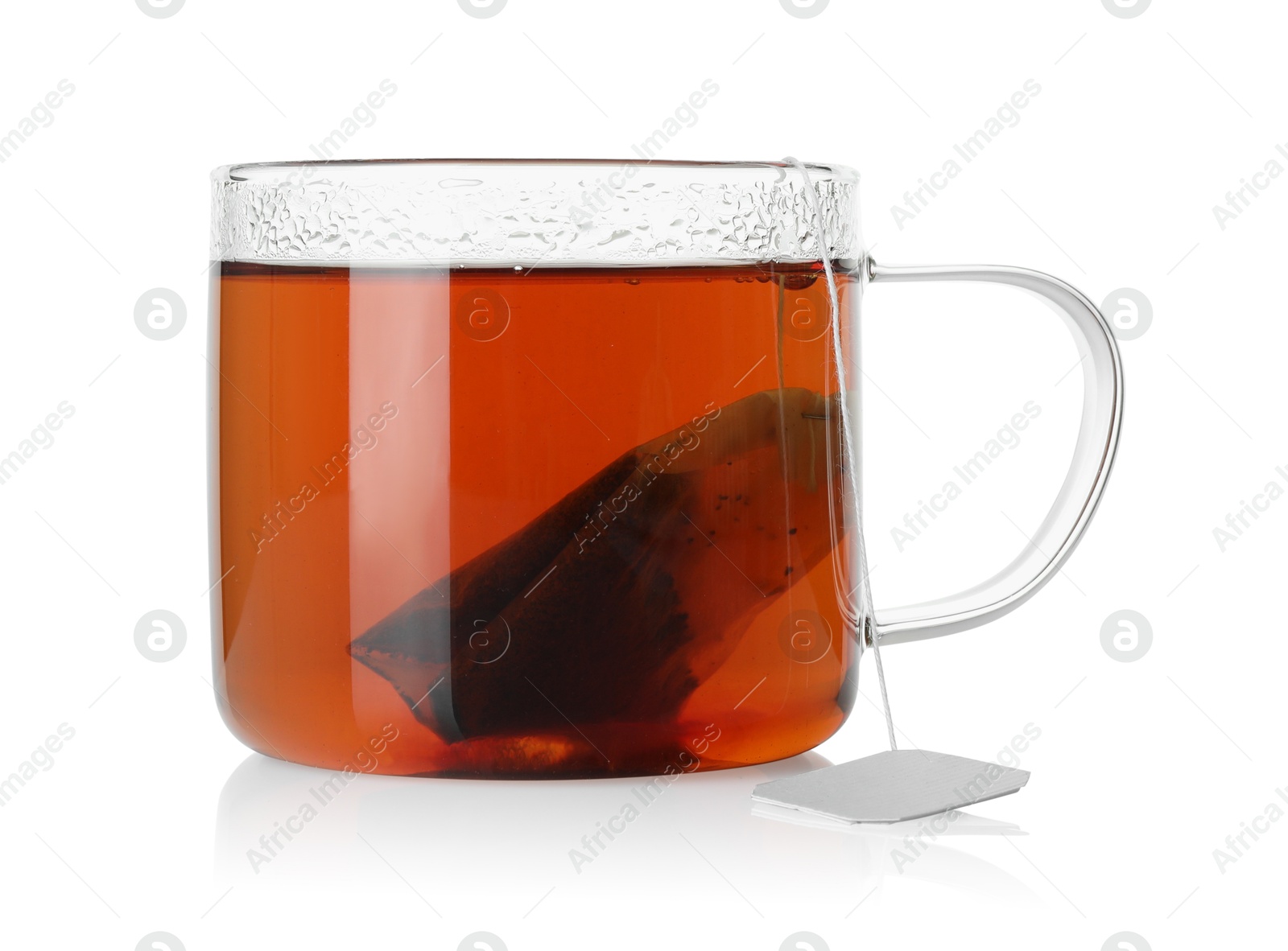 Photo of Tea bag in glass cup with hot drink isolated on white