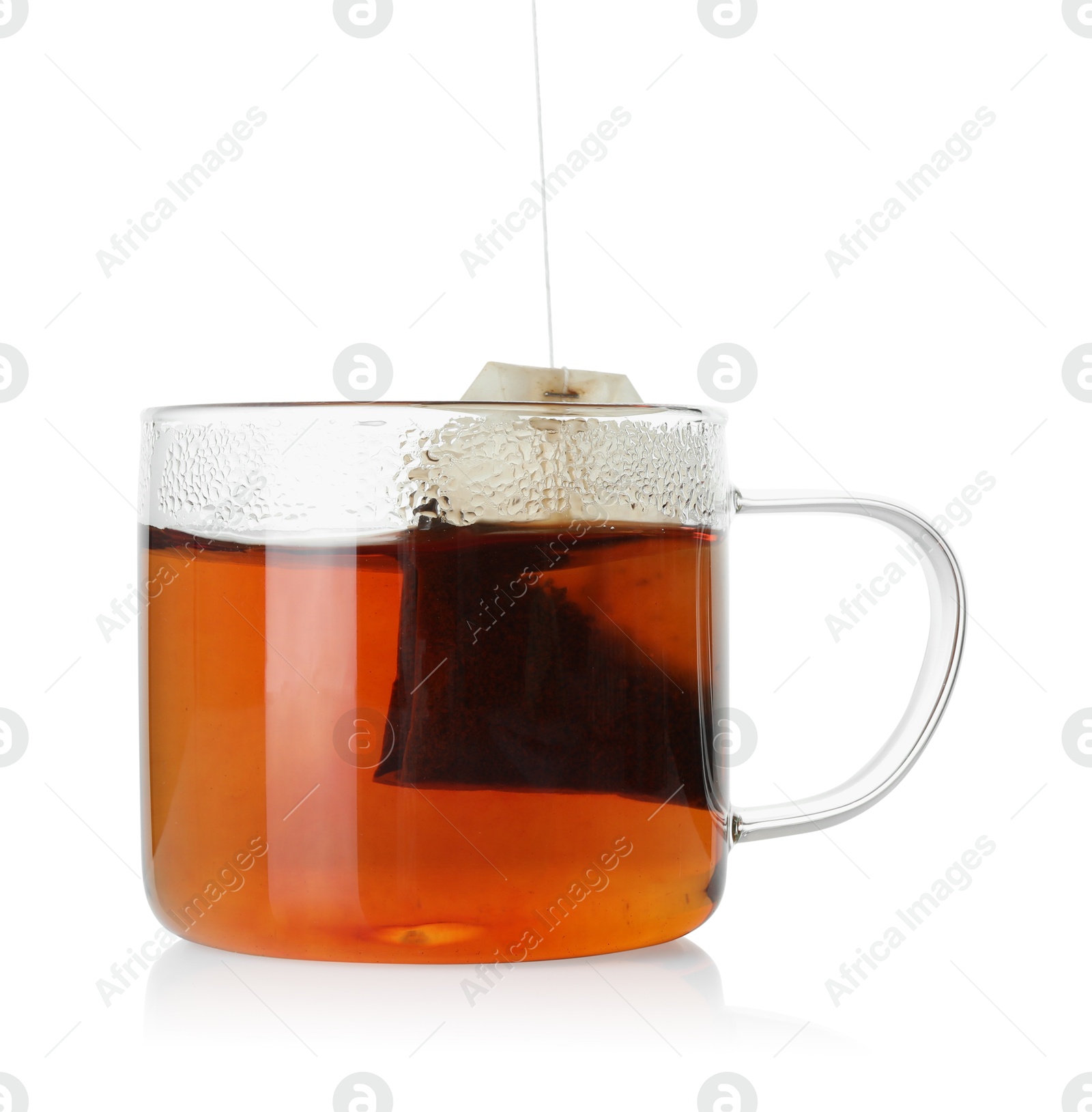 Photo of Putting tea bag into glass cup on white background