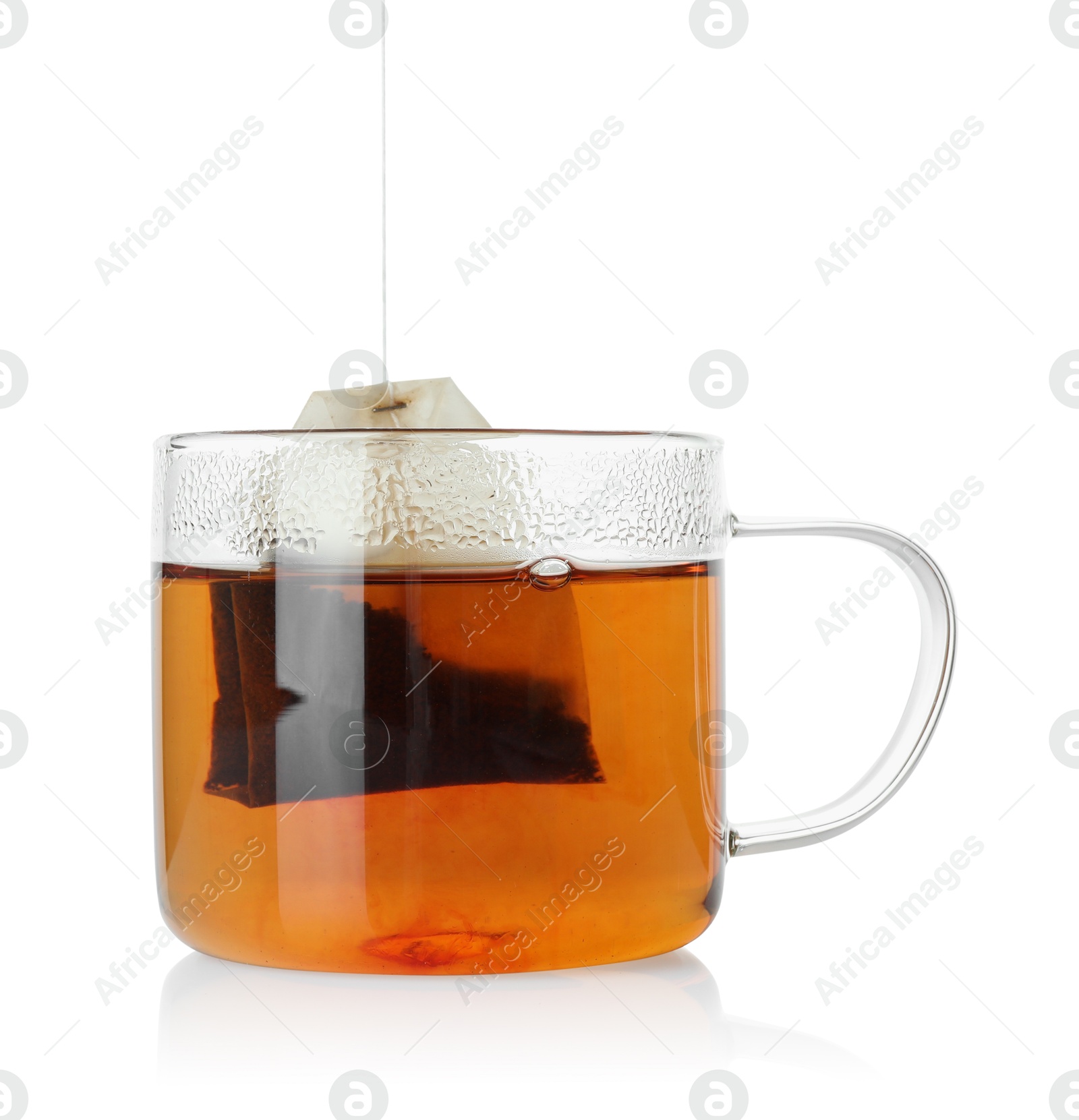 Photo of Putting tea bag into glass cup on white background