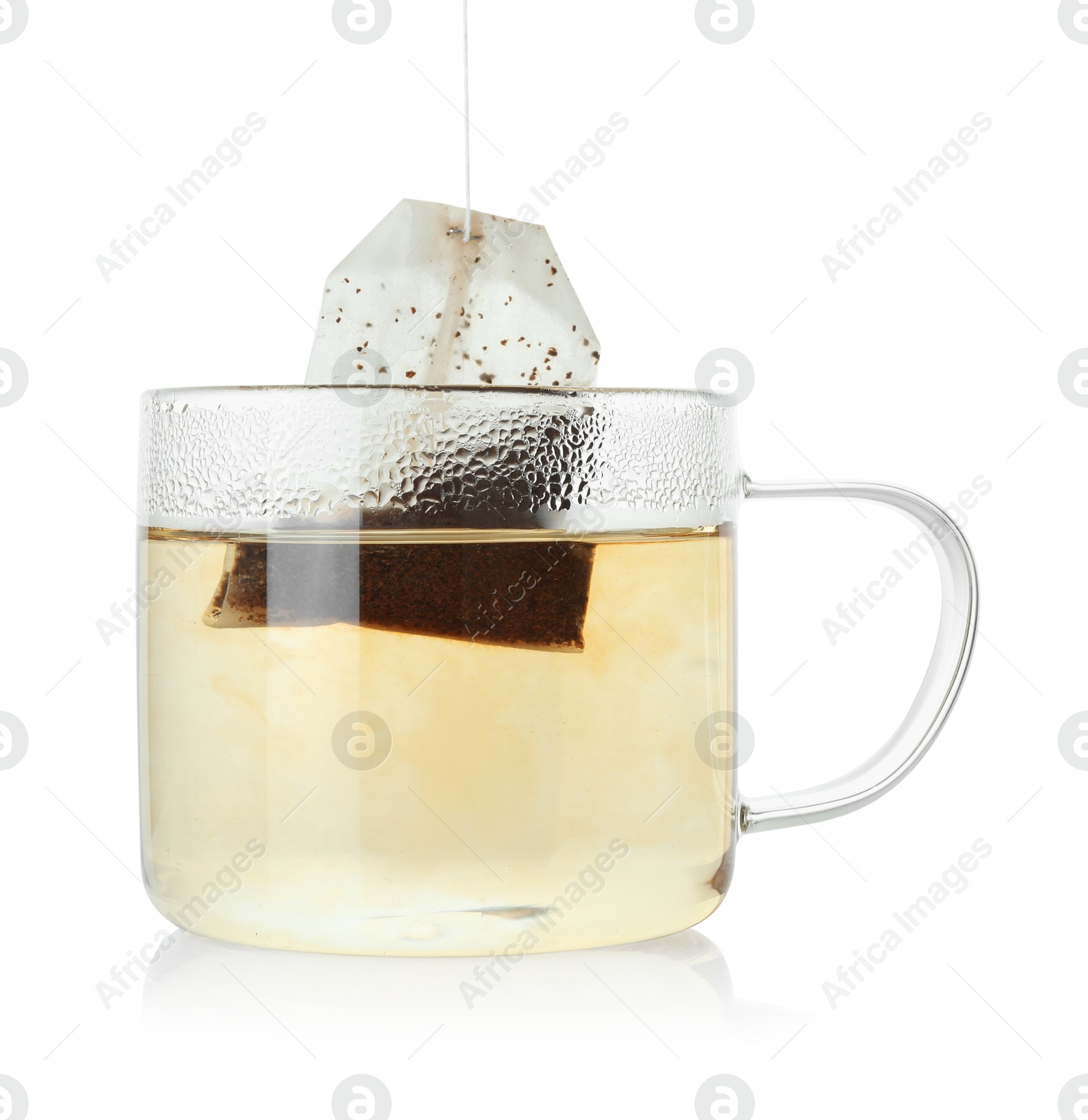 Photo of Putting tea bag into glass cup on white background