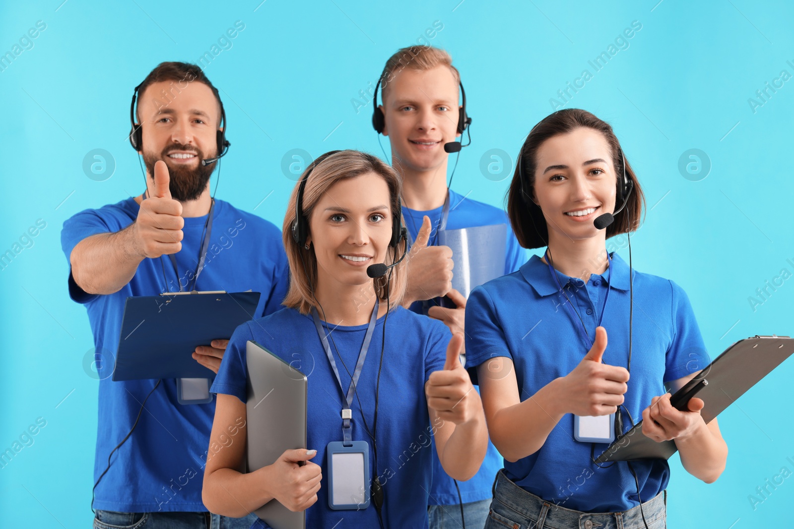 Photo of Technical support call center. Team of friendly operators showing thumbs up on light blue background