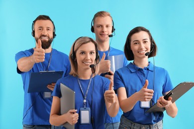 Technical support call center. Team of friendly operators showing thumbs up on light blue background