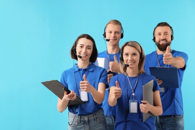 Photo of Technical support call center. Team of friendly operators showing thumbs up on light blue background