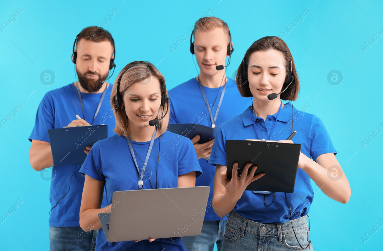 Photo of Technical support call center. Team of friendly operators working on light blue background