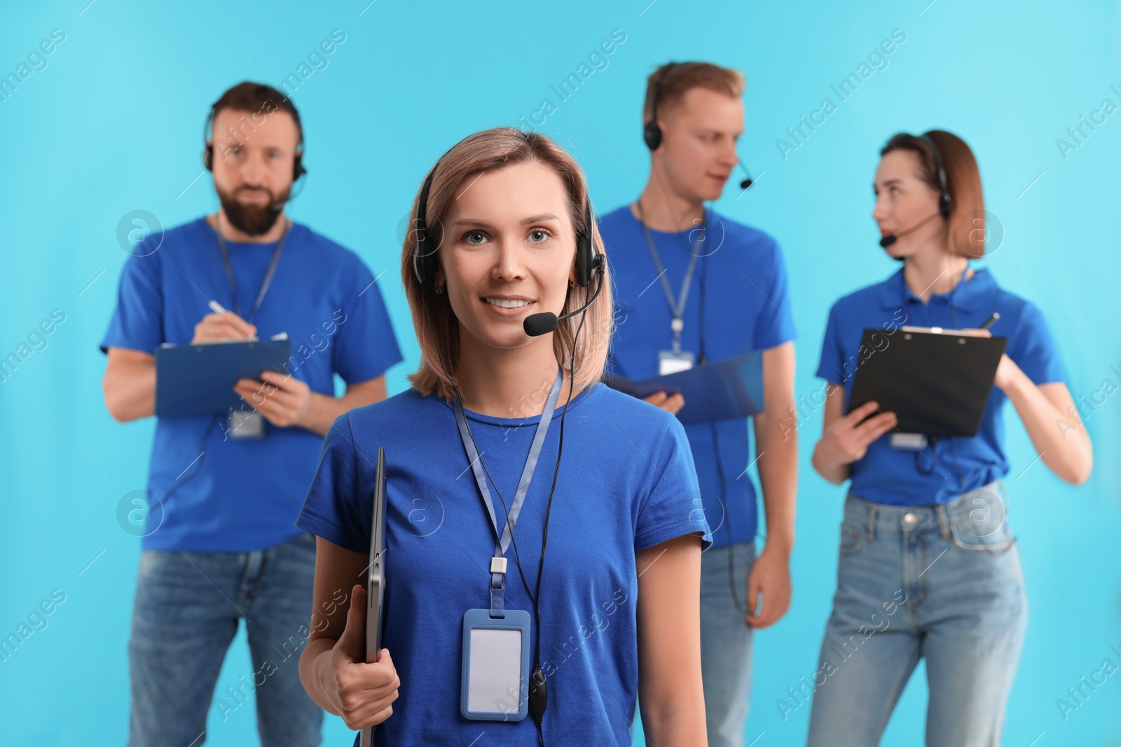 Photo of Technical support call center. Team of friendly operators working on light blue background