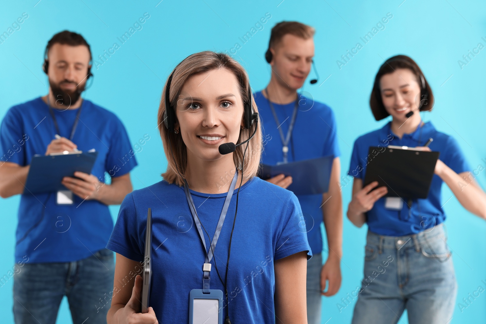 Photo of Technical support call center. Team of friendly operators working on light blue background