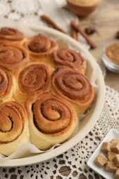 Photo of Freshly baked cinnamon rolls and brown sugar cubes on table, closeup