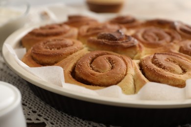 Photo of Freshly baked cinnamon rolls in baking dish on table, closeup