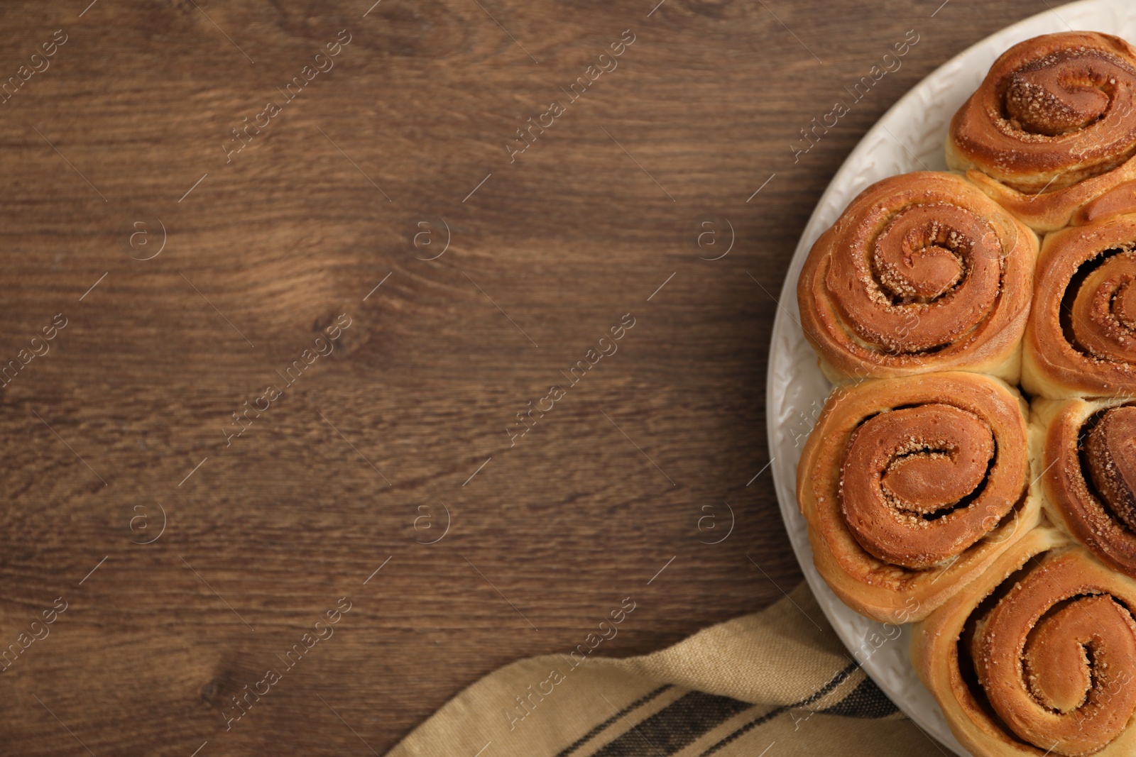 Photo of Freshly baked cinnamon rolls on wooden table, top view. Space for text