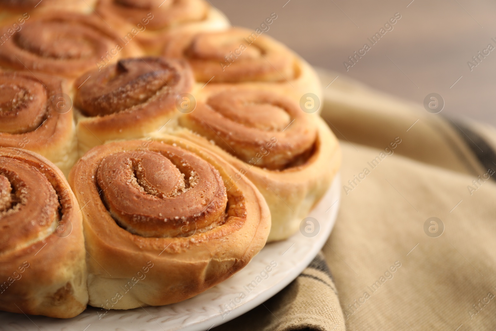 Photo of Freshly baked cinnamon rolls and napkin on blurred background, closeup