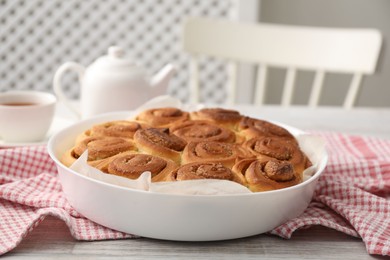 Photo of Freshly baked cinnamon rolls on light wooden table, closeup