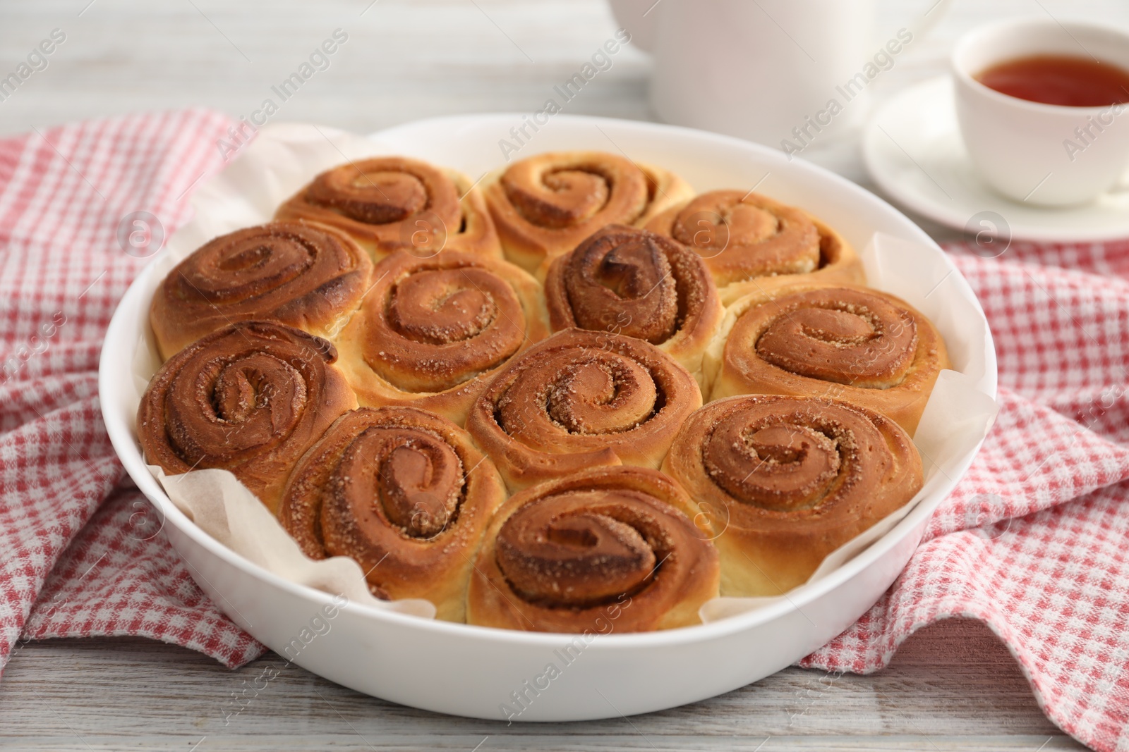 Photo of Freshly baked cinnamon rolls on light wooden table, closeup