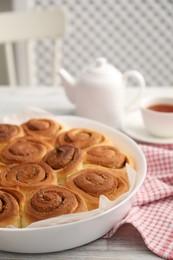 Photo of Freshly baked cinnamon rolls on light wooden table indoors, closeup