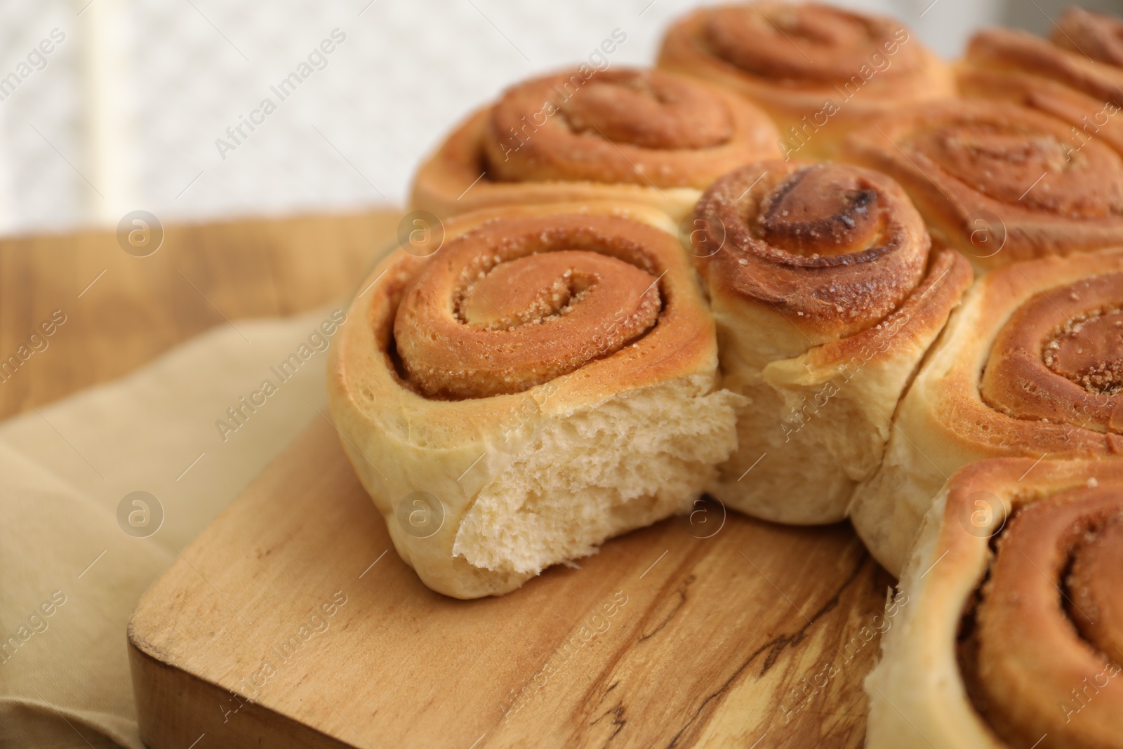 Photo of Freshly baked cinnamon rolls on wooden board, closeup