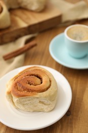 Photo of Freshly baked cinnamon roll on wooden table, closeup