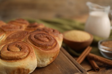 Photo of Freshly baked cinnamon rolls on wooden table, closeup