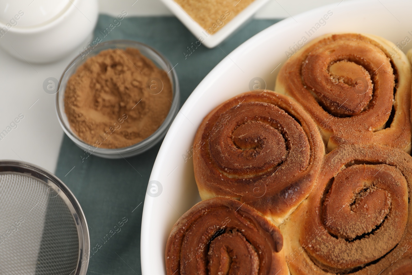 Photo of Tasty cinnamon rolls and spices on white table, flat lay