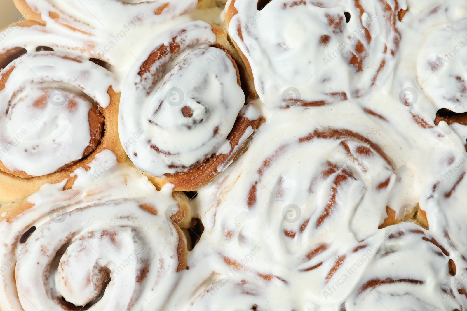 Photo of Delicious frosted cinnamon rolls as background, top view