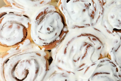 Photo of Delicious frosted cinnamon rolls as background, top view