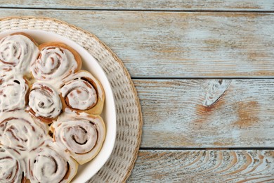 Photo of Delicious frosted cinnamon rolls in baking dish on wooden rustic table, top view. Space for text