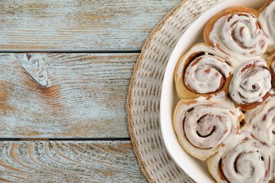 Photo of Delicious frosted cinnamon rolls in baking dish on wooden rustic table, top view. Space for text