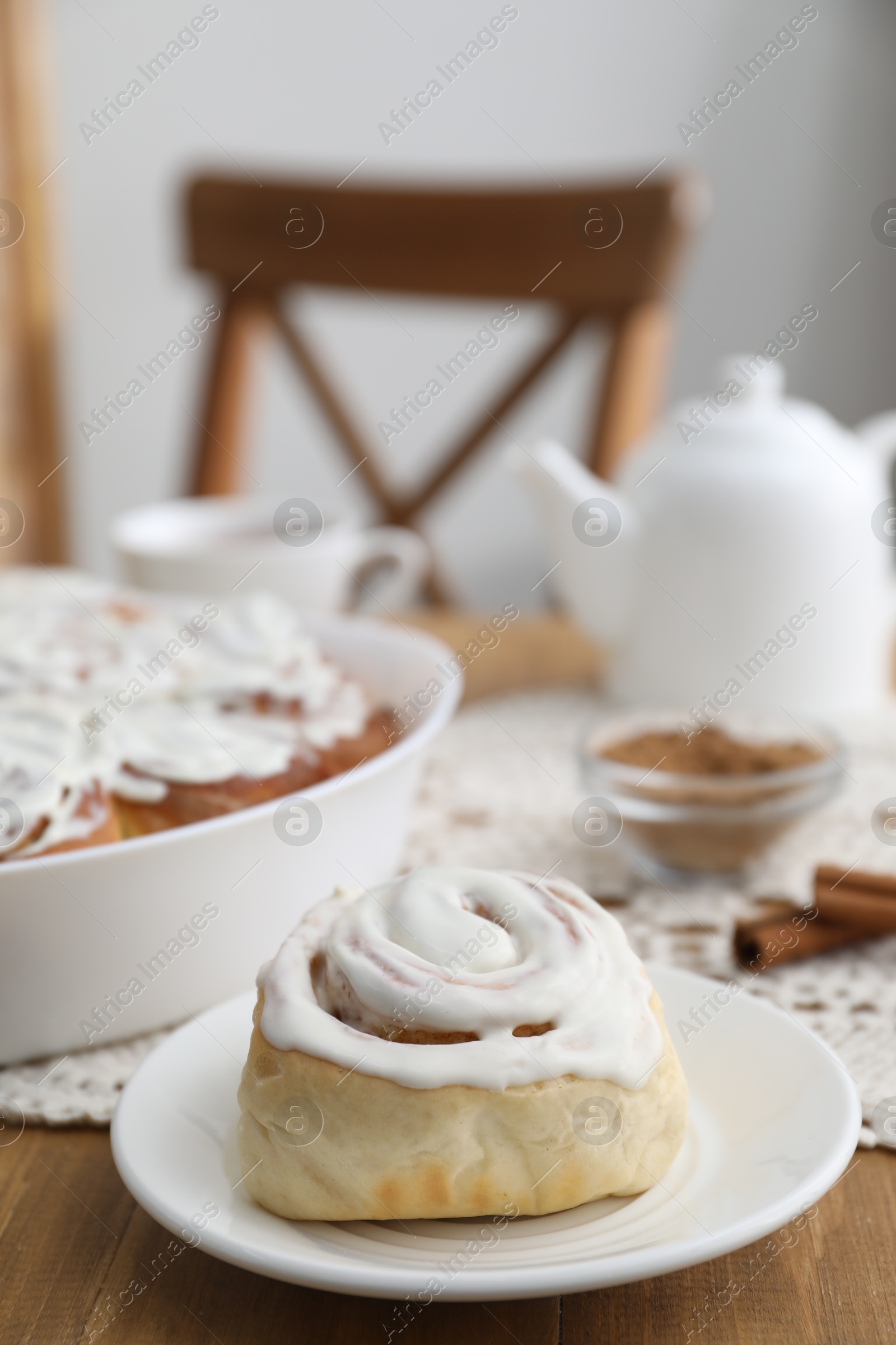 Photo of Delicious frosted cinnamon rolls on wooden table indoors, closeup