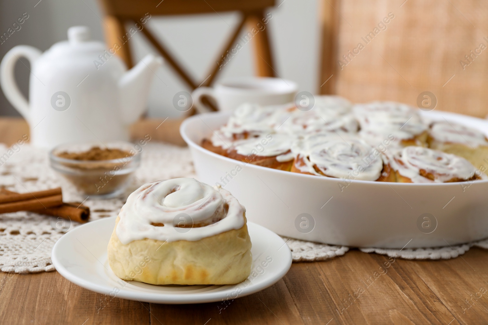 Photo of Delicious frosted cinnamon rolls on wooden table indoors, closeup