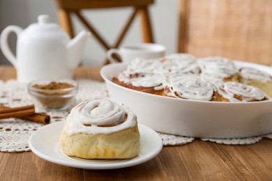 Photo of Delicious frosted cinnamon rolls on wooden table indoors, closeup