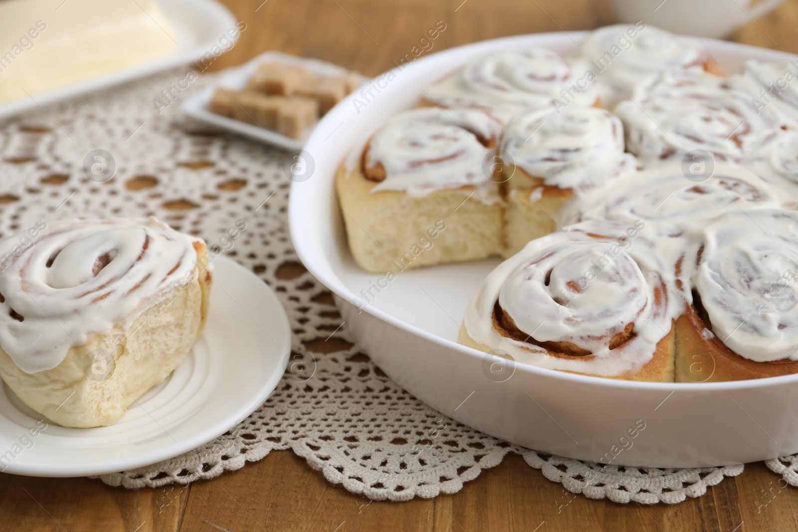 Photo of Delicious frosted cinnamon rolls on wooden table, closeup