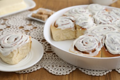 Photo of Delicious frosted cinnamon rolls on wooden table, closeup