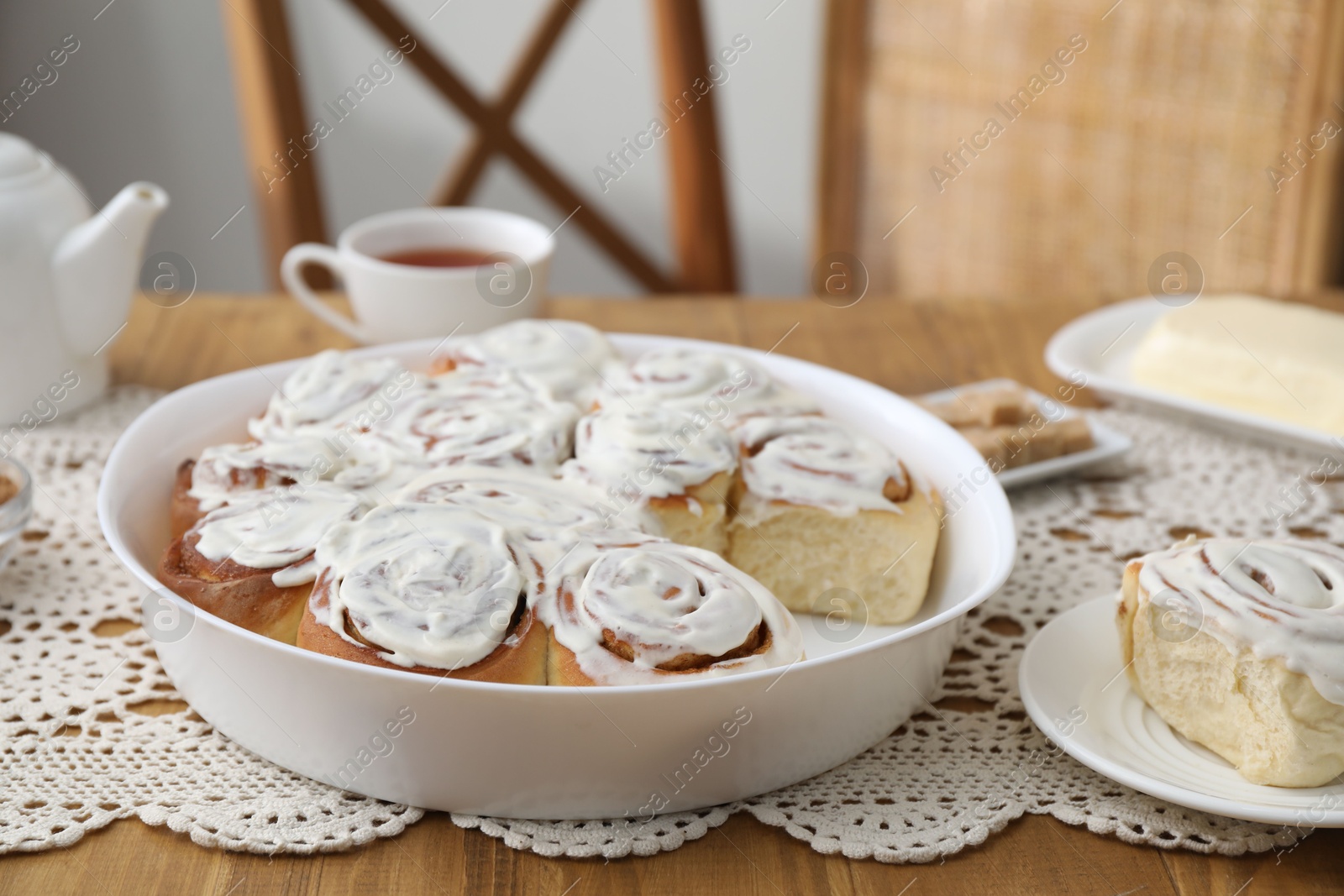 Photo of Delicious frosted cinnamon rolls on wooden table indoors, closeup