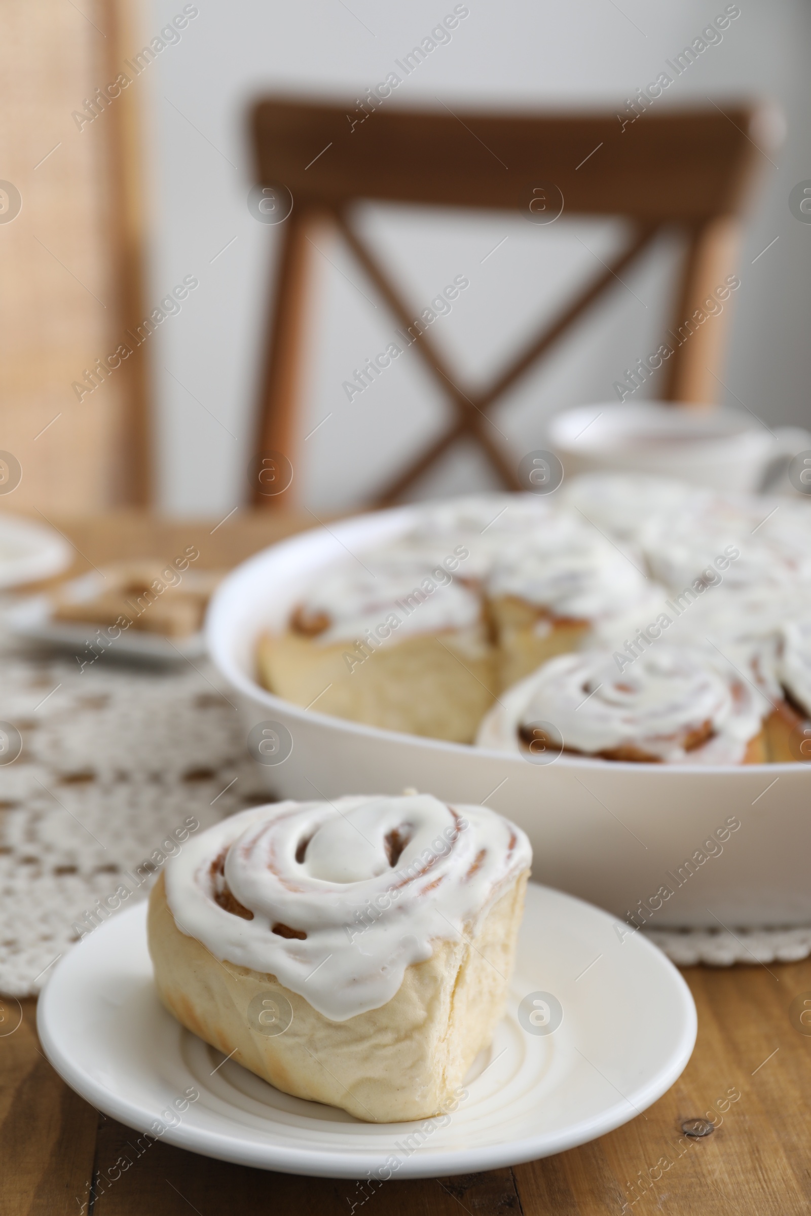 Photo of Delicious frosted cinnamon rolls on wooden table indoors, closeup