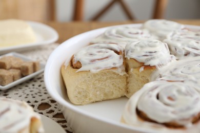 Photo of Delicious frosted cinnamon rolls on table, closeup