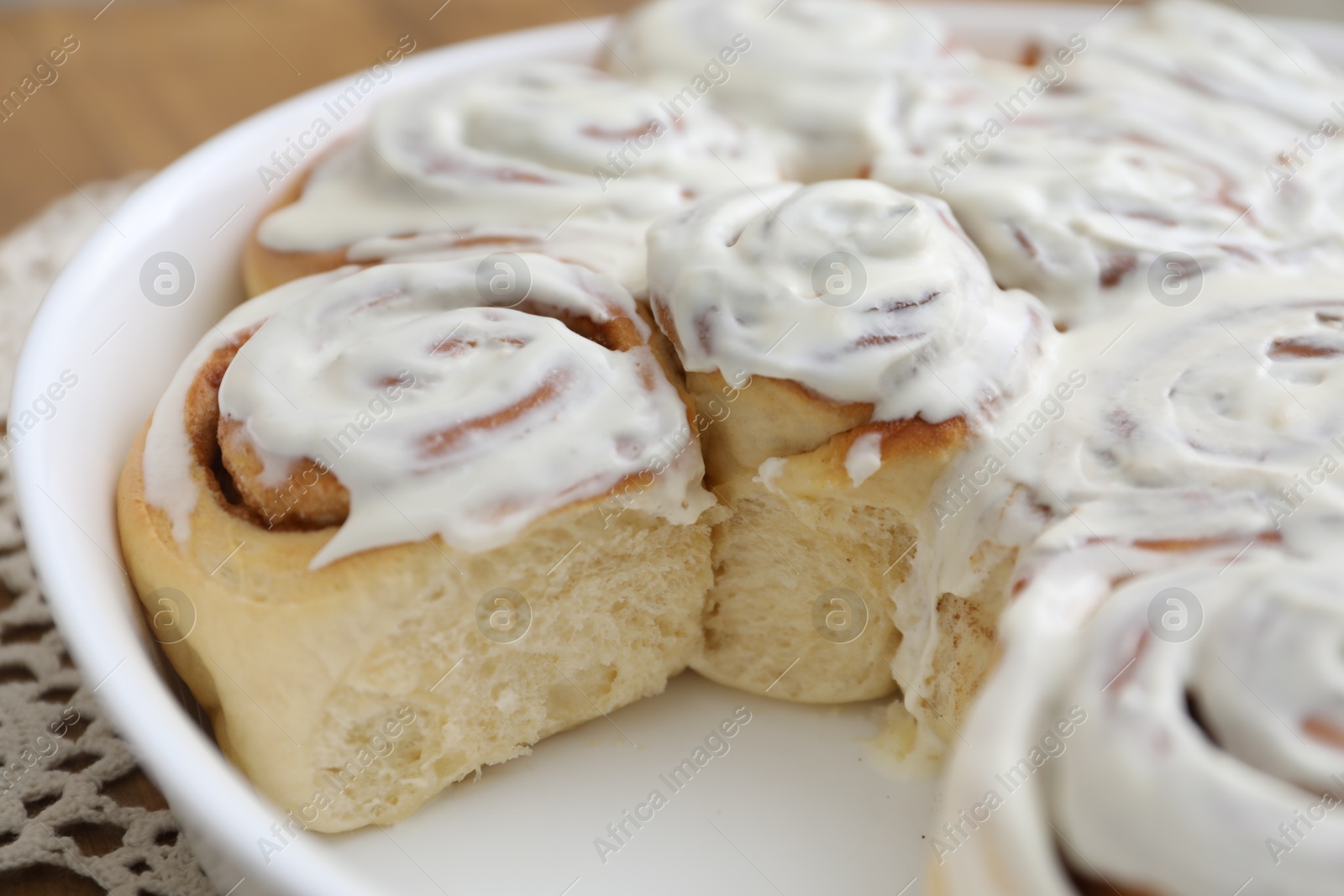 Photo of Delicious frosted cinnamon rolls on table, closeup