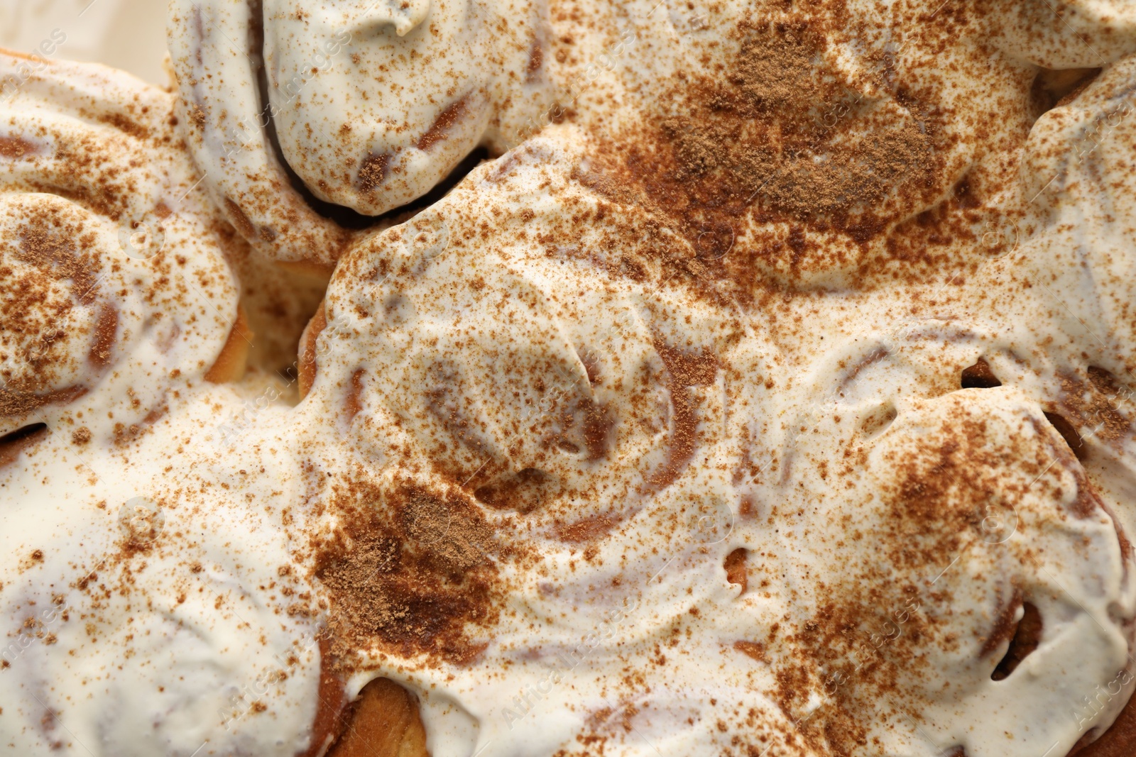 Photo of Delicious frosted cinnamon rolls as background, top view