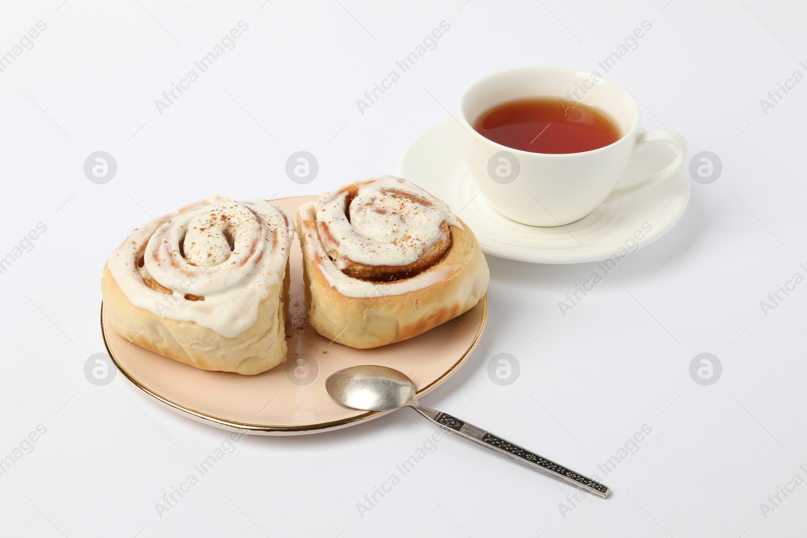 Photo of Delicious frosted cinnamon rolls and tea on white table