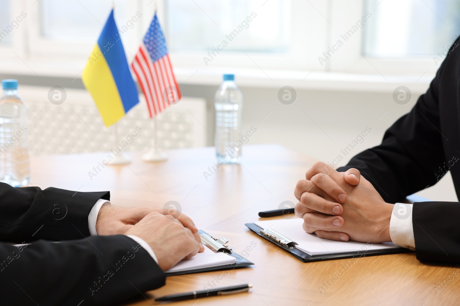 Photo of Diplomats negotiating during meeting at wooden table indoors, closeup