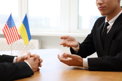 Diplomats negotiating during meeting at wooden table indoors, closeup