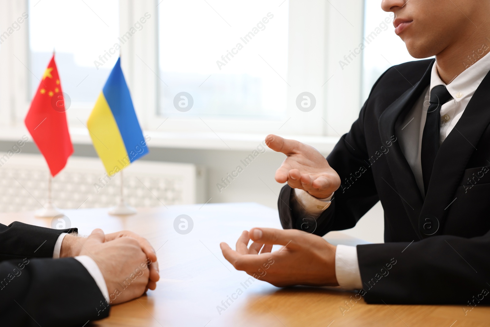 Photo of Diplomats negotiating during meeting at wooden table indoors, closeup