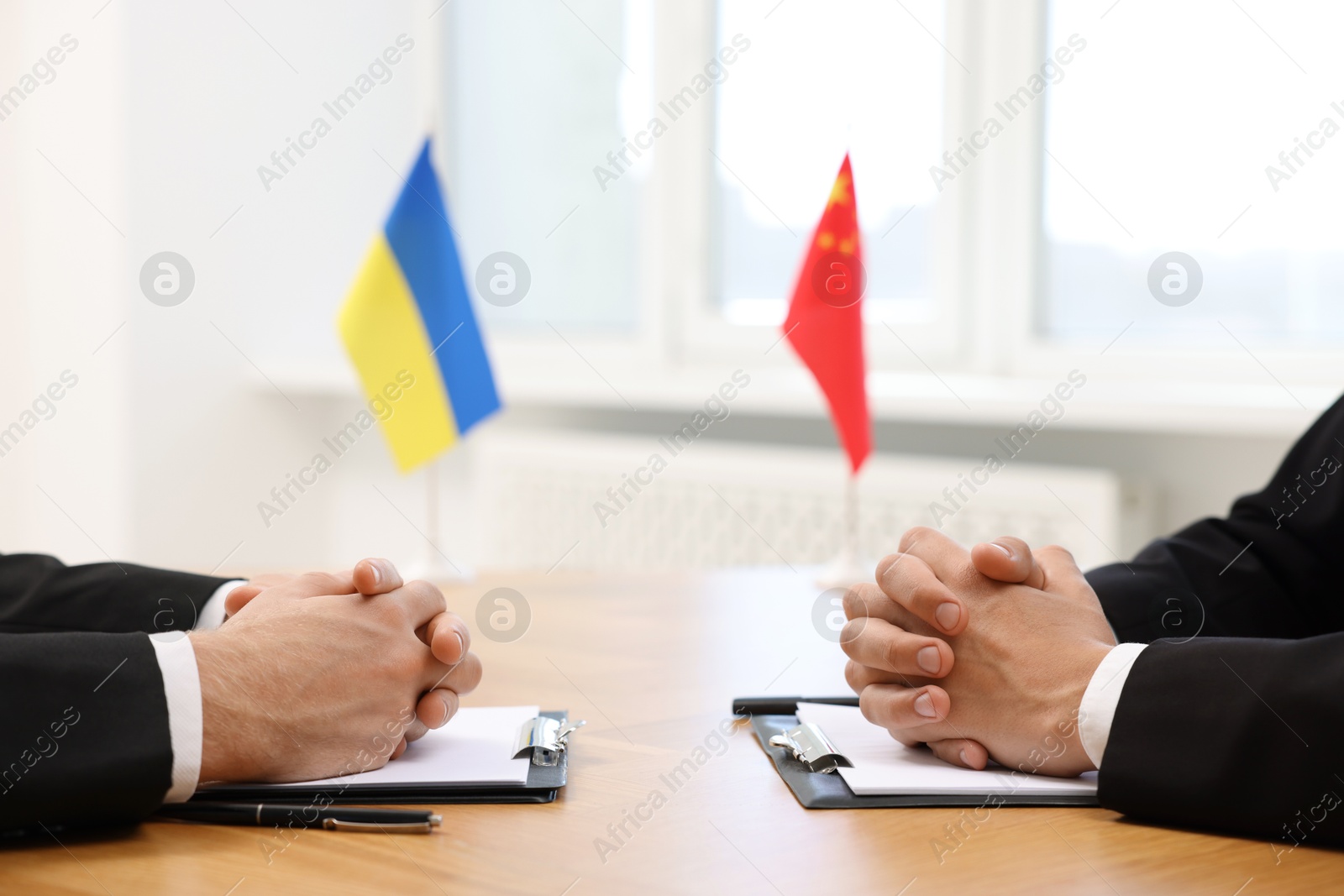 Photo of Diplomats negotiating during meeting at wooden table indoors, closeup